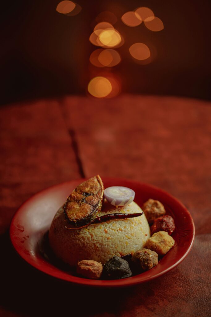 Indulge in a classic Bengali dish featuring rice, fish, and spices, elegantly plated on a red dish.